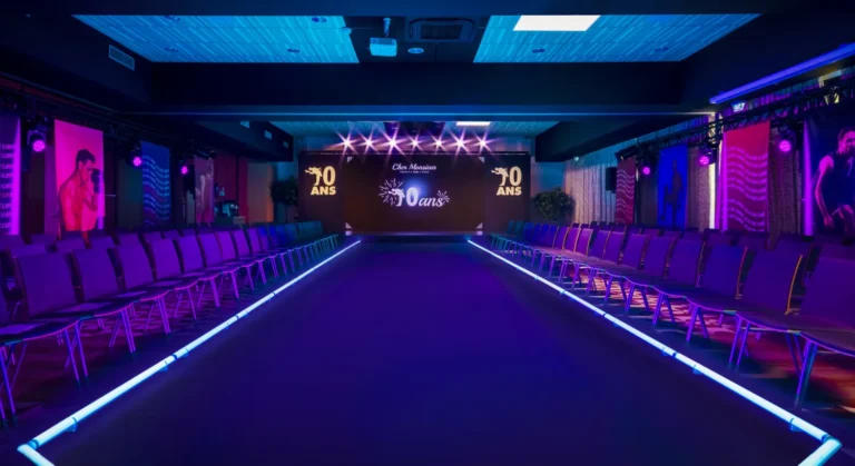 Défilé événementiel avec podium central éclairé en violet et bleu, ambiance immersive avec éclairages LED et scène au fond.